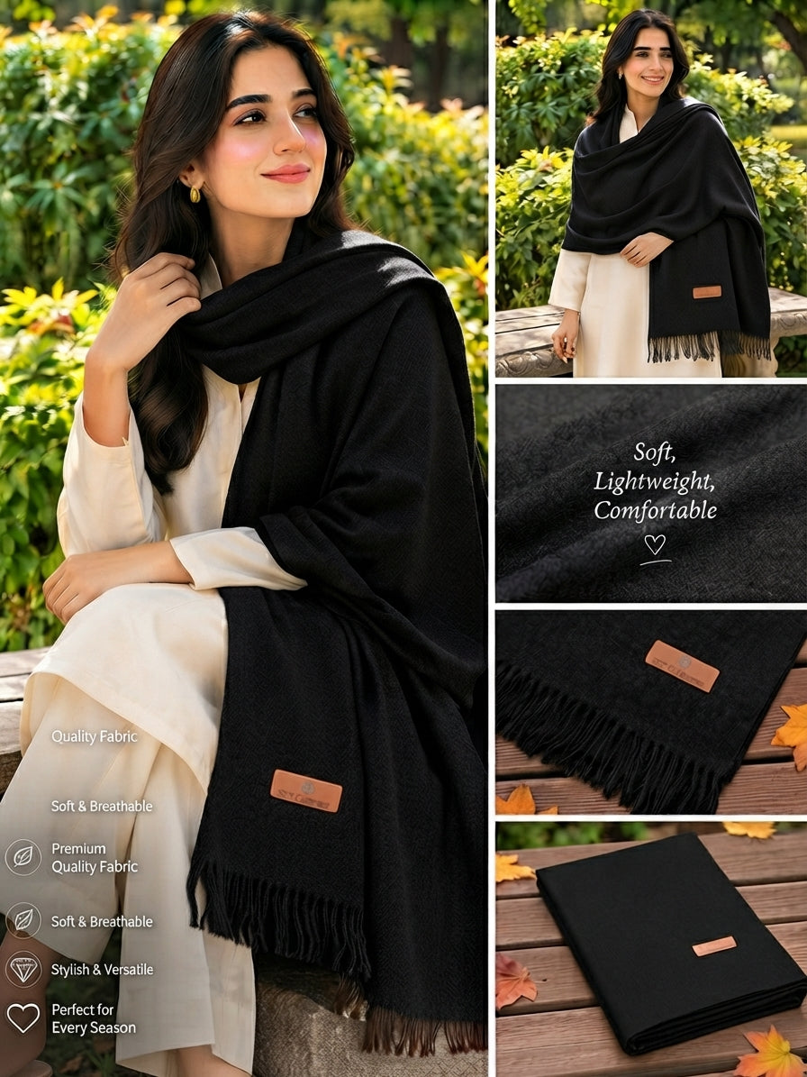 A black lightweight shawl or pashmina scarf with fringe, shown worn by a woman outdoors and in a collage of detail shots. The collage includes close-ups of the fabric texture, a small tan brand patch, and the scarf folded on a wooden surface.